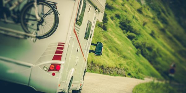 Camper Van on the Road. Class C Motorhome Coach with Bikes on the Rear Side Bike Rack. Family RV Travel.